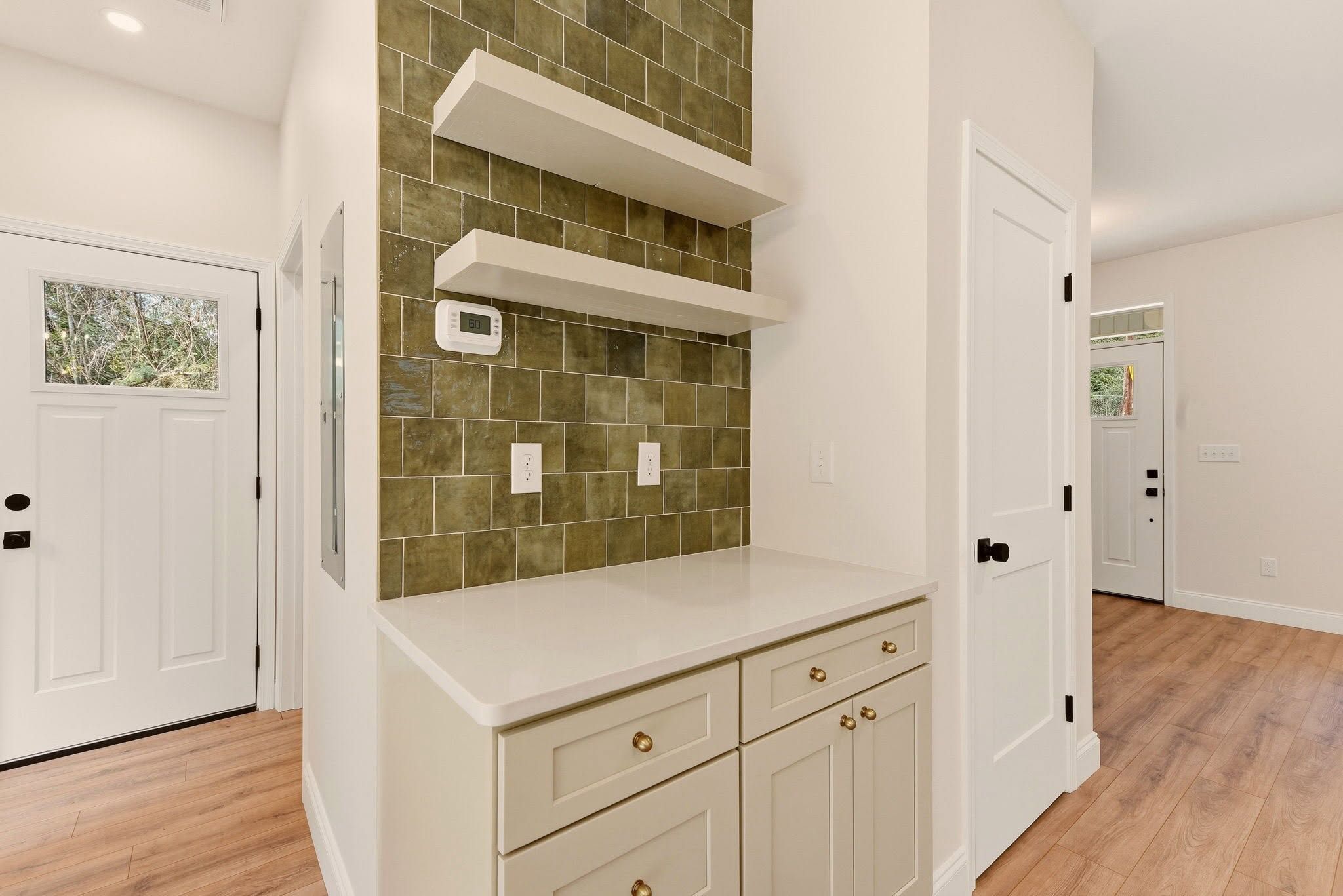 Coffee bar with green square tile, floating shelves, and shaker cabinets