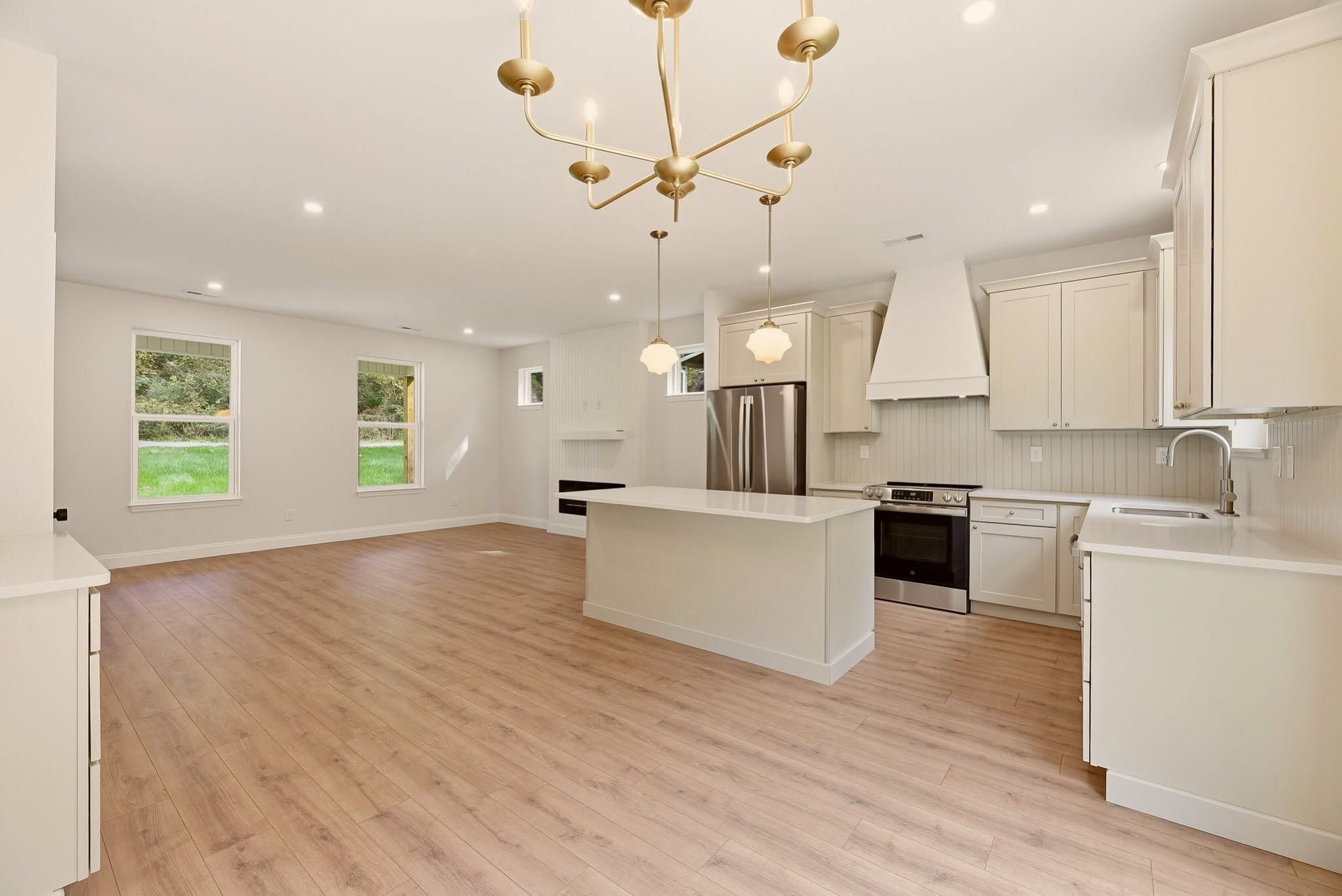 Cream shaker kitchen with an island, plastered range hood, and brass chandelier