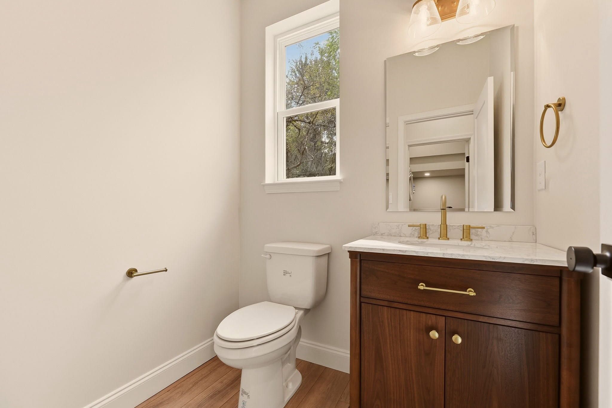 Finished powder room with a walnut vanity and brass fixtures